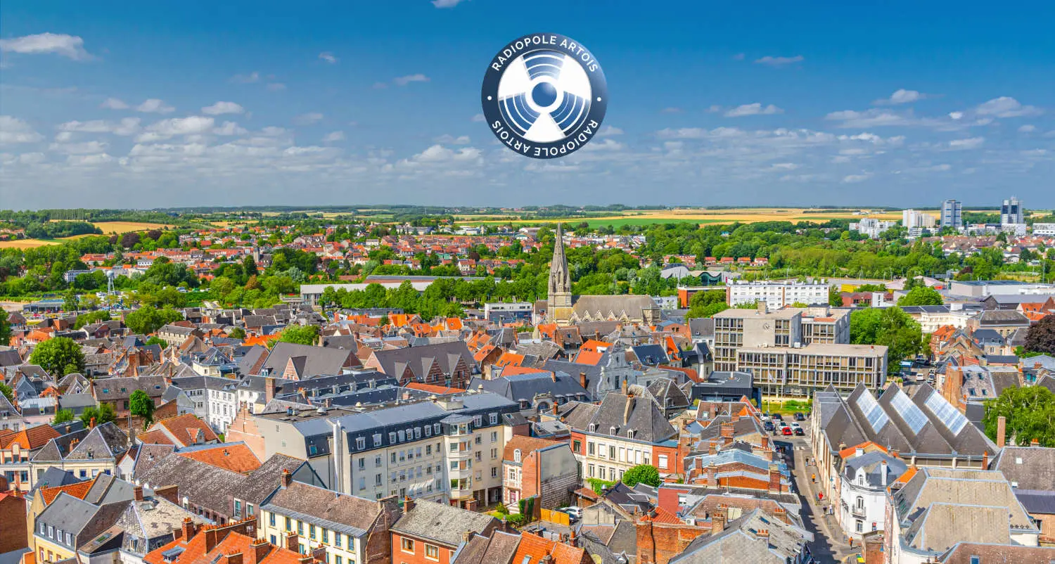 Aerial panoramic view of Arras city historical centre, historic quarter with old buildings and Eglise Saint-Gery Saint Gaugericus catholic church, green parks and fields, blue sky, Hauts-de-France
